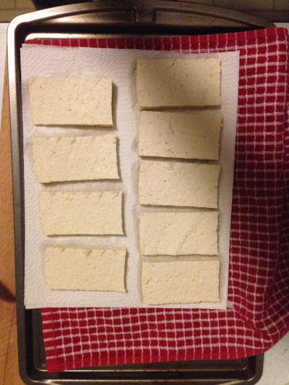 Put down a cloth towel on a hard surface (I use a baking sheet) and lay paper towels three thick on top. Place the tofu slices on top of the paper towels.